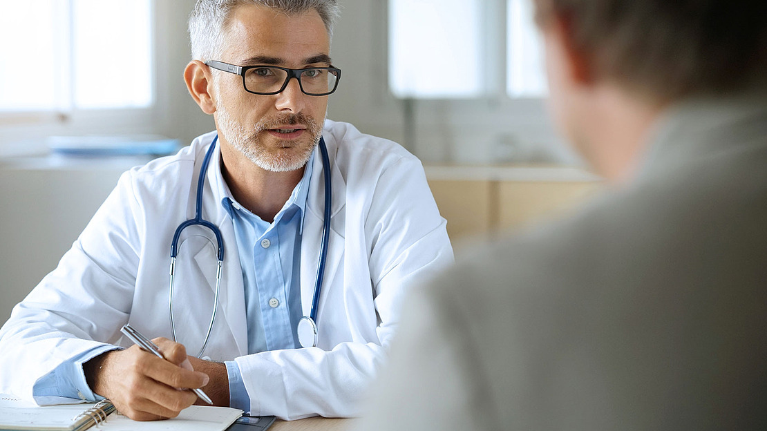 Ein Arzt im Arztkittel berät einen Patienten