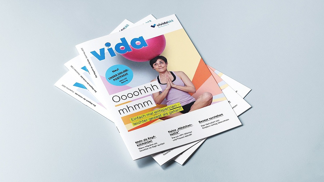 Ein Stapel "vida"-Magazine liegt auf einer hellblauen Fläche. Das oberste Titelbild zeigt eine Frau in Yogaposition mit einem rosafarbenen Gymnastikball und einem Text über Entspannung und Tipps für einen gesunden Lebensstil.