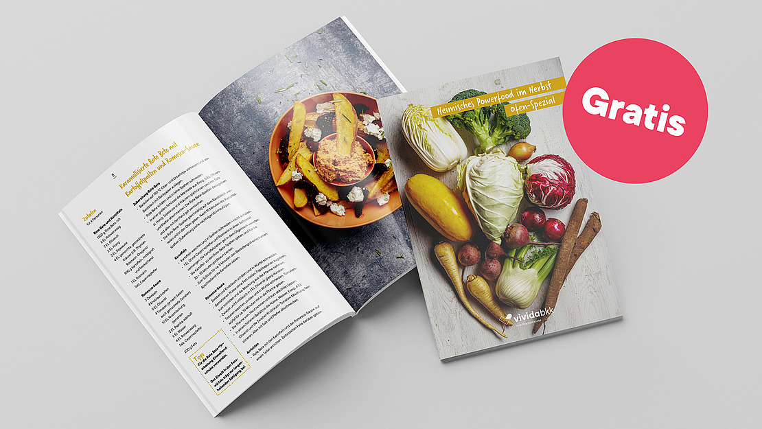 Es sind zwei Rezepthefte abgebildet, von denen das eine eine Rezeptseite zeigt und das andere ein Cover mit buntem Gemüse. Ein großer rosafarbener Kreis mit dem Wort "Gratis" befindet sich auf der rechten Seite des Bildes.
