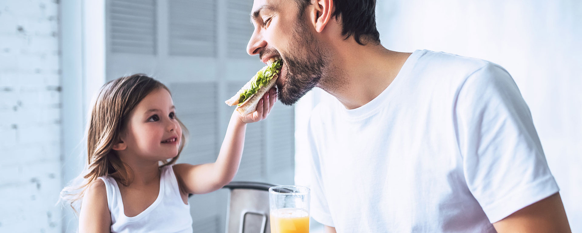 Junges Mädchen lässt ihren Vater von ihrem Brot abbeißen