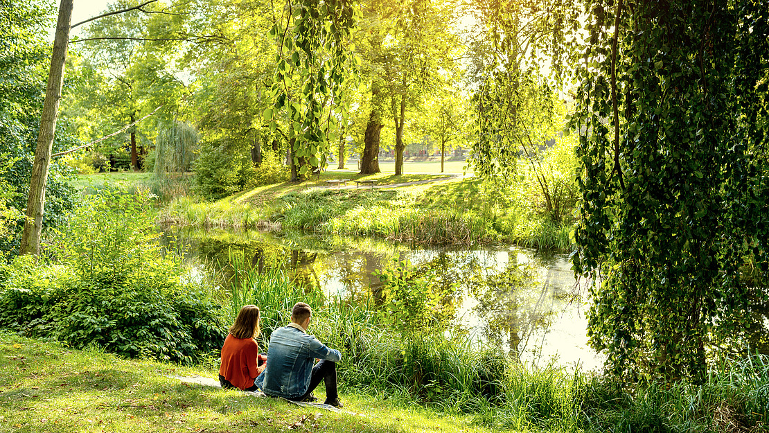 Pärchen sitzt am Fluss-Ufer