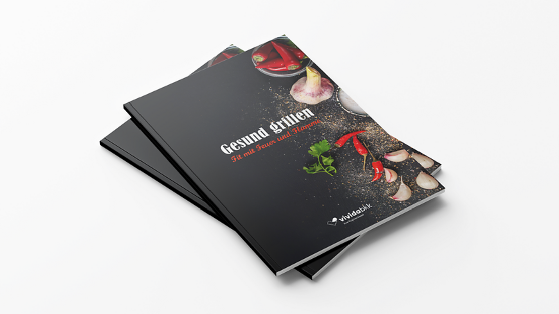 Zwei schwarze Kochbücher mit dem Titel "Gesund grillen: Fit mit Feuer und Flamme" mit Abbildungen von Gewürzen, Chilischoten, Knoblauch und Kräutern auf dem Einband, gestapelt auf einer weißen Fläche.