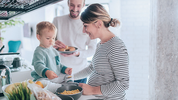 Pärchen kocht. Das kleine Kind hilft beim Kochen.