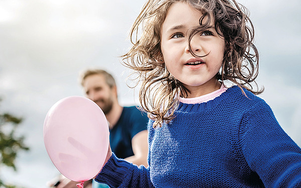 Ein kleines Mädchen mit einem rosa Luftballon