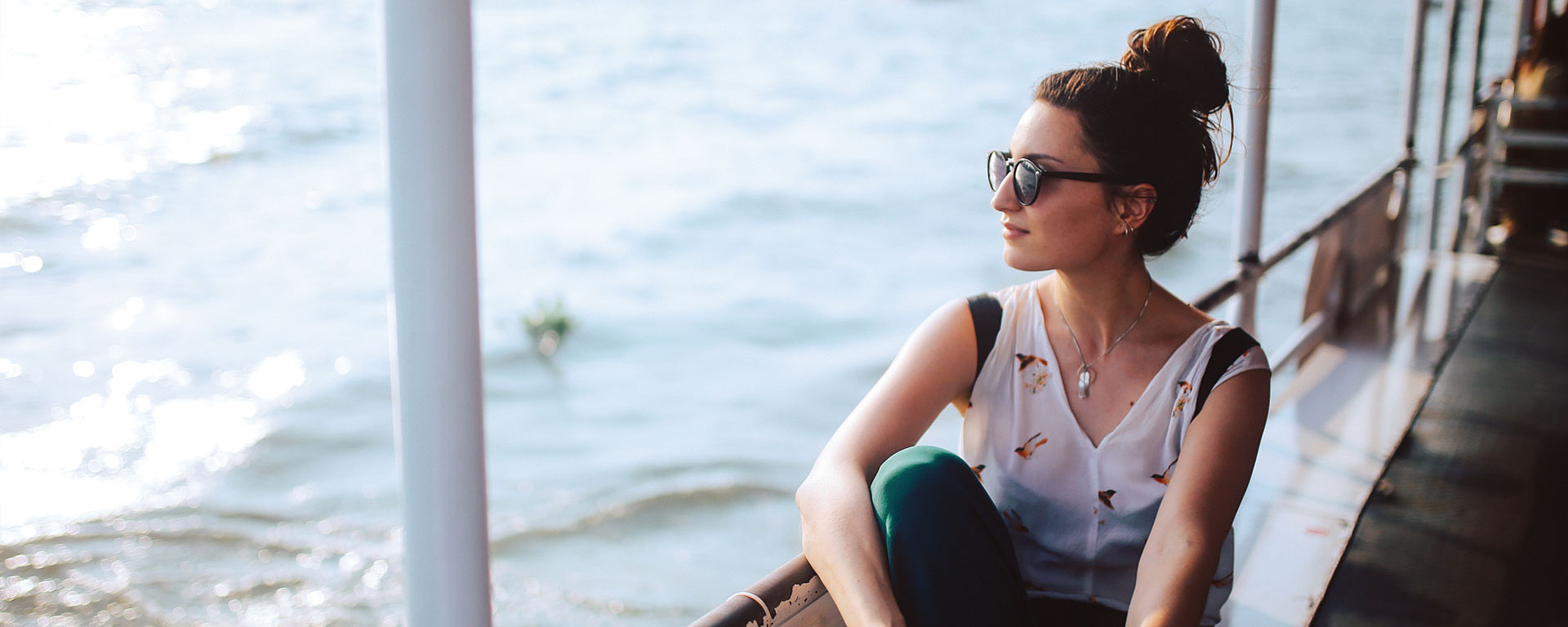 Junge Frau mit Sonnenbrille auf einem Schiff