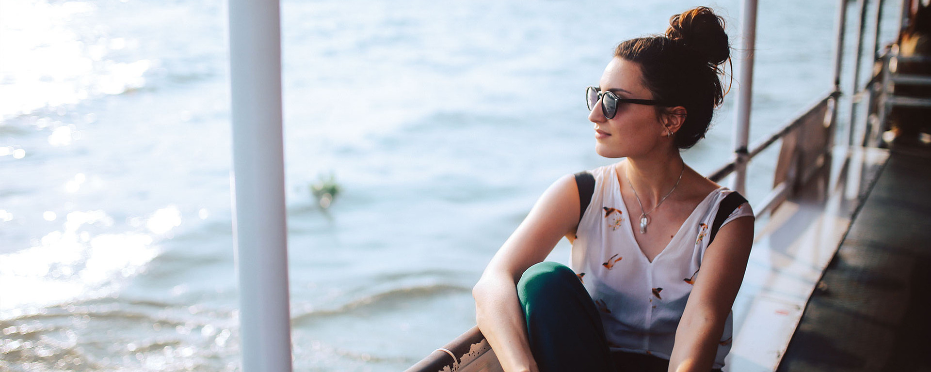 Junge Frau mit Sonnenbrille auf einem Schiff