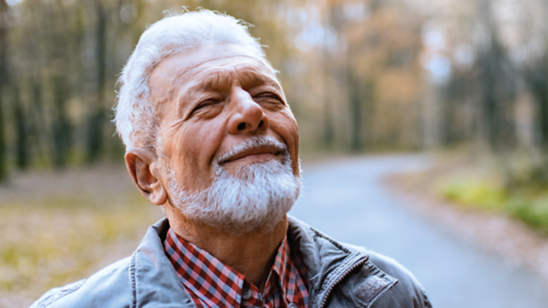 Ein älterer Mann mit grauem Haar und Bart lächelt, während er auf einem Waldweg steht. Der Text lautet: "Infobaustein COPD: Körperliche Aktivität. Bewegung und Sport." In der rechten oberen Ecke befindet sich das Logo des vivida bkk.