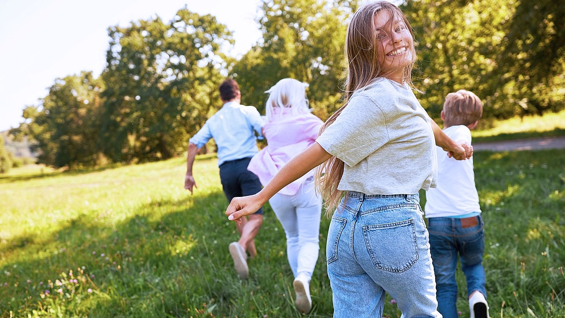 Familie läuft auf einer Sommerwiese