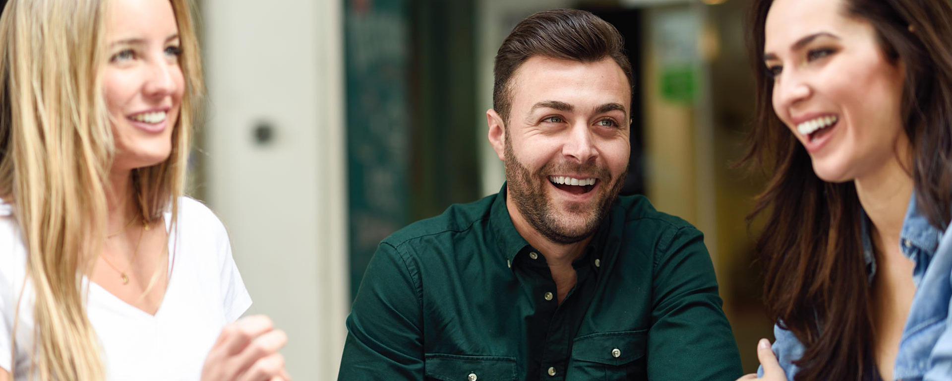 Zwei junge Frauen und ein Mann sitzen in einem Café